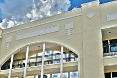 Top of 3 story building with art deco design and arched walkway