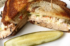 chicken sandwich on toated rye bread with pickle spear