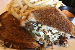 meatloaf sandwich topped with coleslaw on toasted rye bread with side of fires